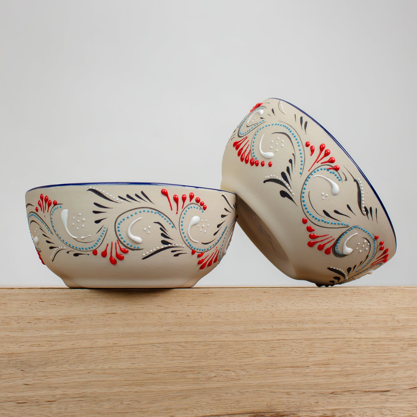 Two ceramic bowls with hand painted decorative patterns on a wooden counter