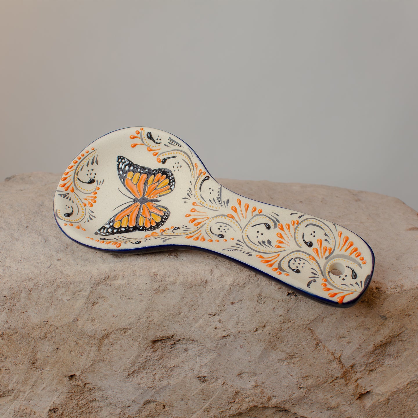 Decorative spoon rest with butterfly design on a stone surface