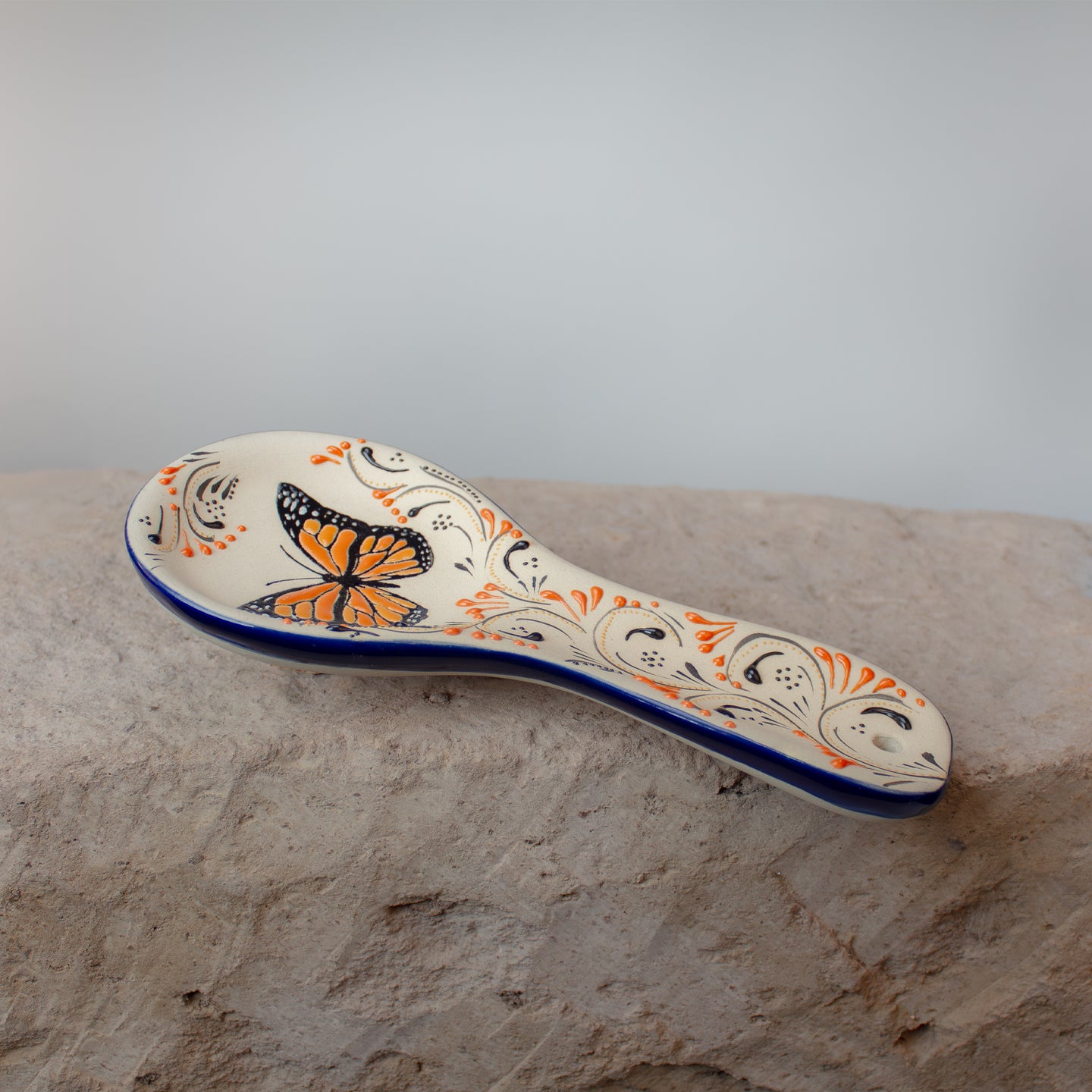Butterfly-patterned ceramic spoon rest on stone kitchen countertop.