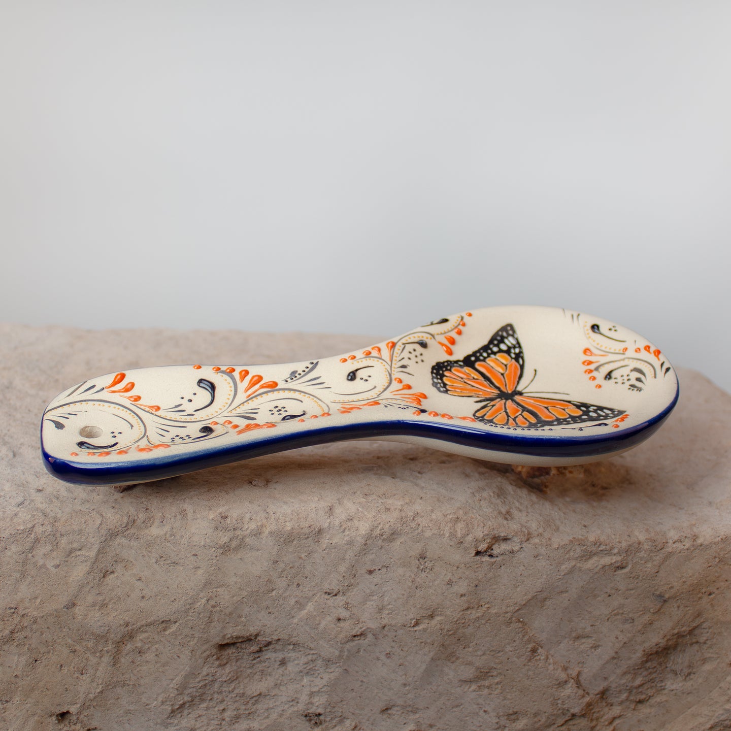 Beige ceramic spoon rest on a wooden surface.