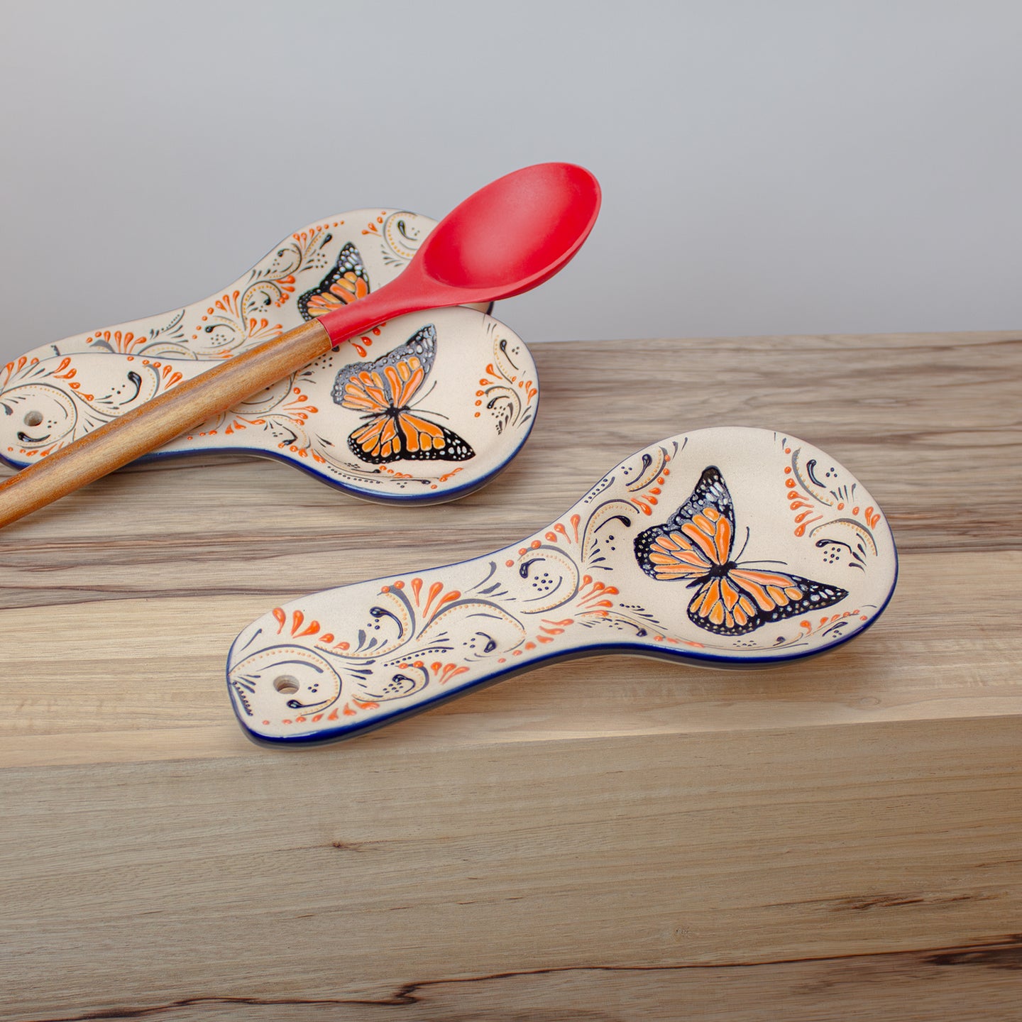 Monarch Butterfly-patterned ceramic spoon rests on a wooden surface.