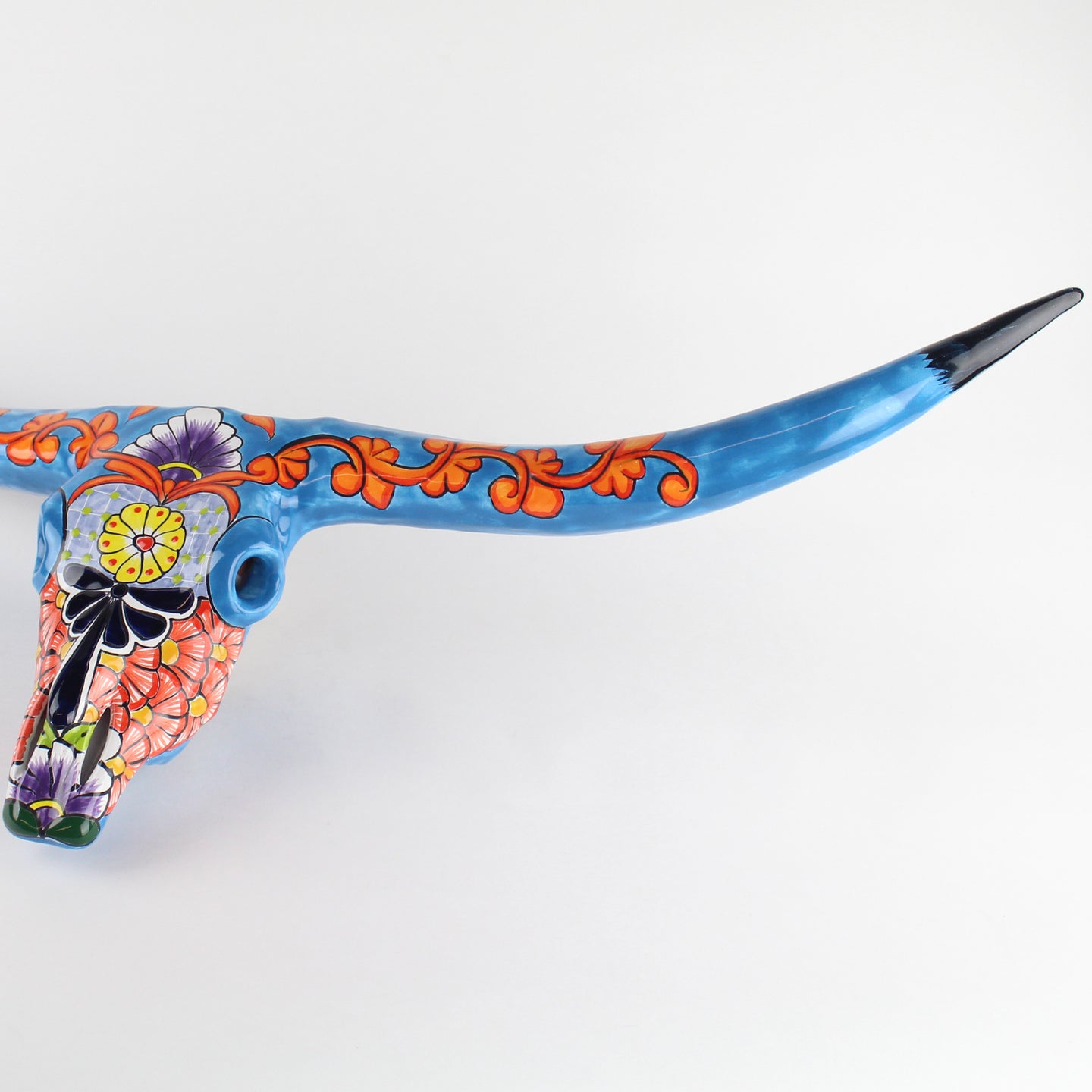 Wall hanging cow skull with colorful Talavera patterns on a white background