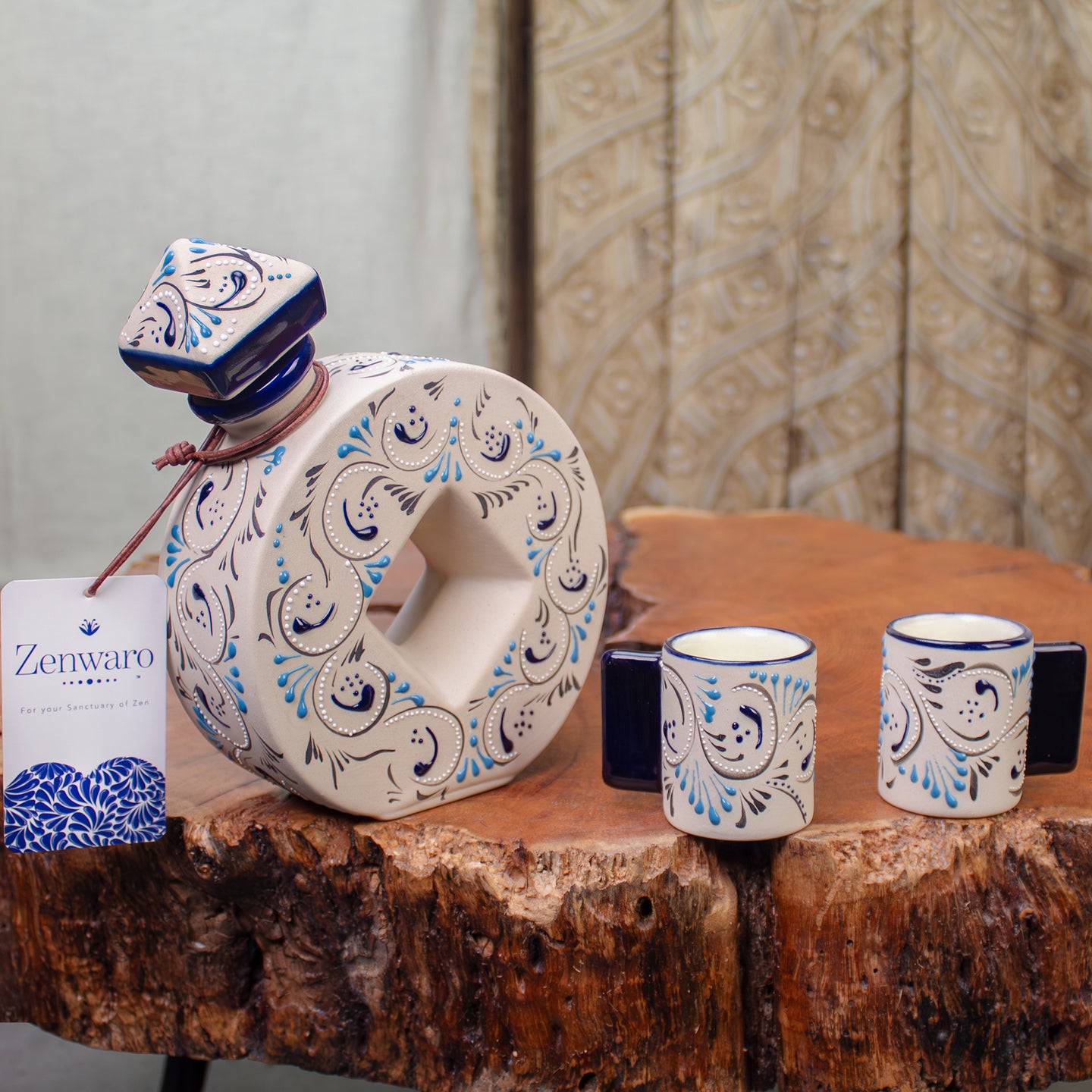 Ceramic drinkware set including a large decorative bottle and two matching shooters with blue turquoise and black swirl patterns on white, displayed on a rustic wood table with Zenwaro branded tag included.