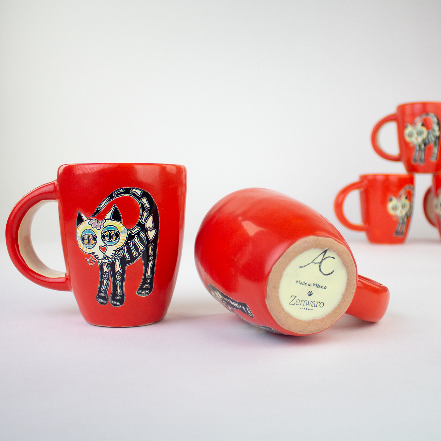 Ceramic mugs hand painted in red with Day of Dead cat illustrations.