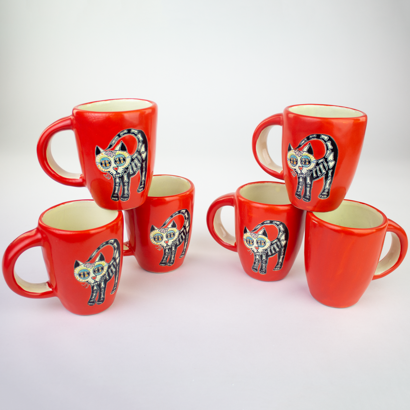 Set of red ceramic mugs with cat illustrations.
