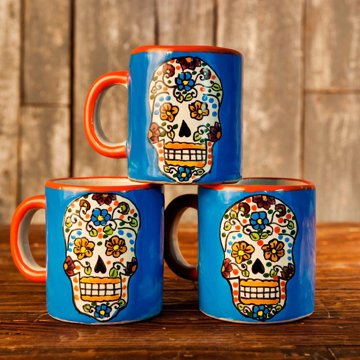Talavera mugs with orange handles and Dia de los Muertos designs.