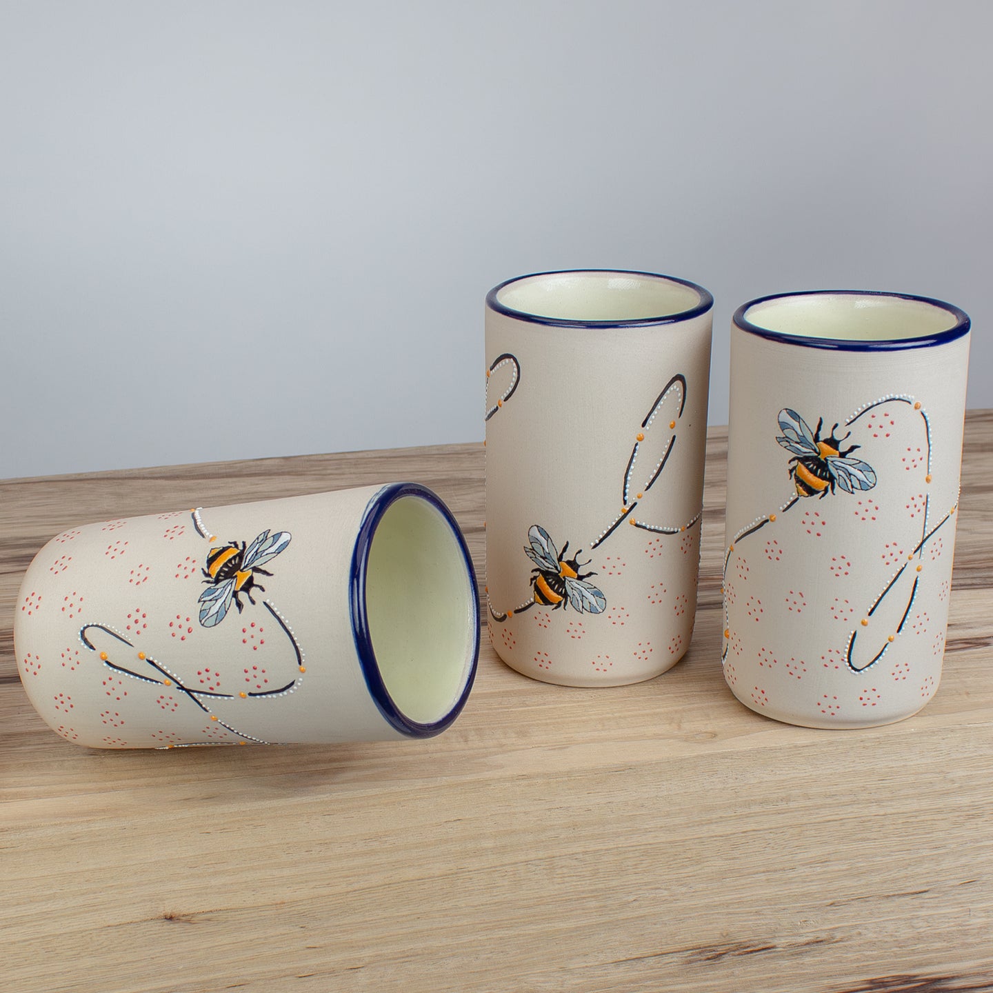 Ceramic tumbler with bee designs on a wooden counter.