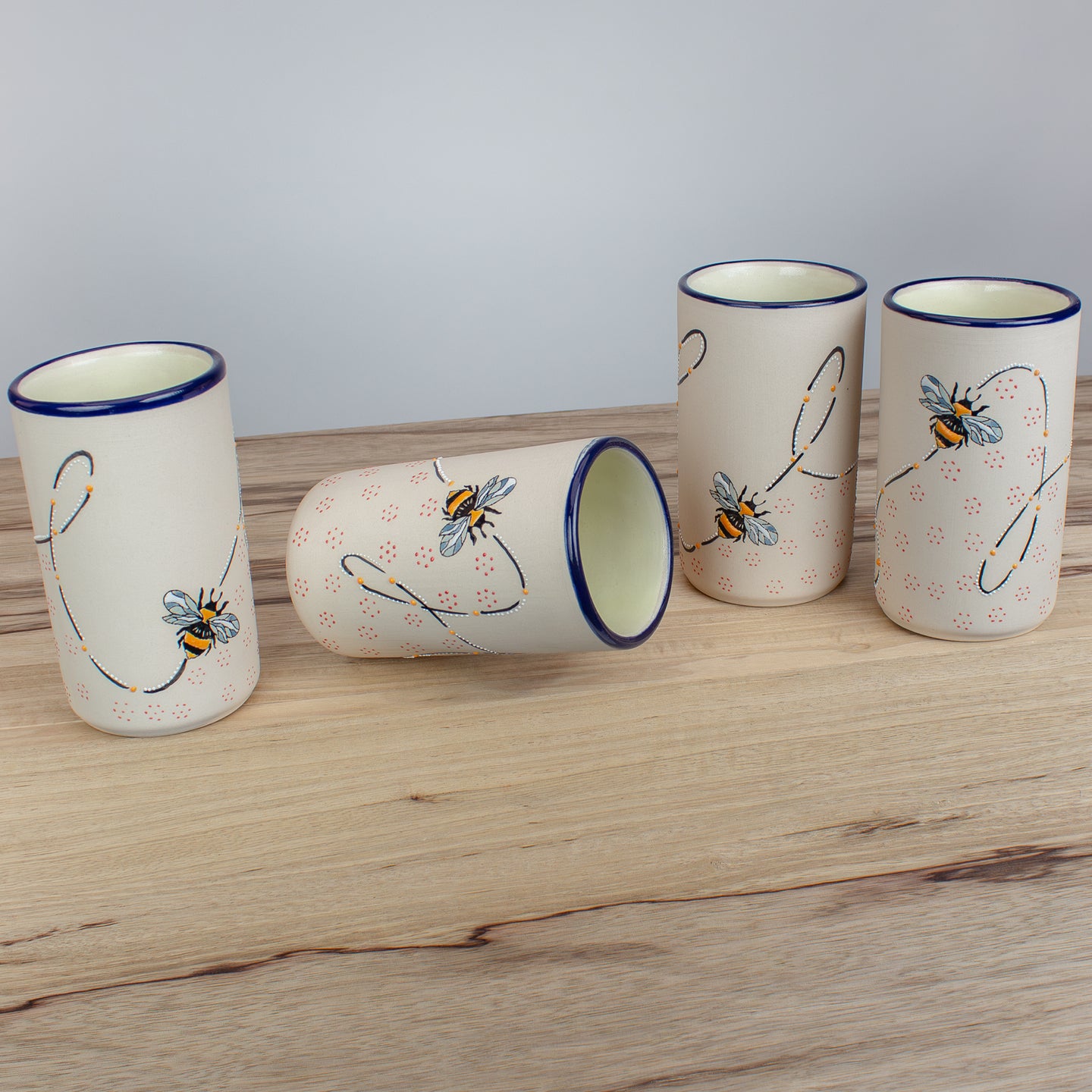 Ceramic drinkware with bee designs on a wooden counter.