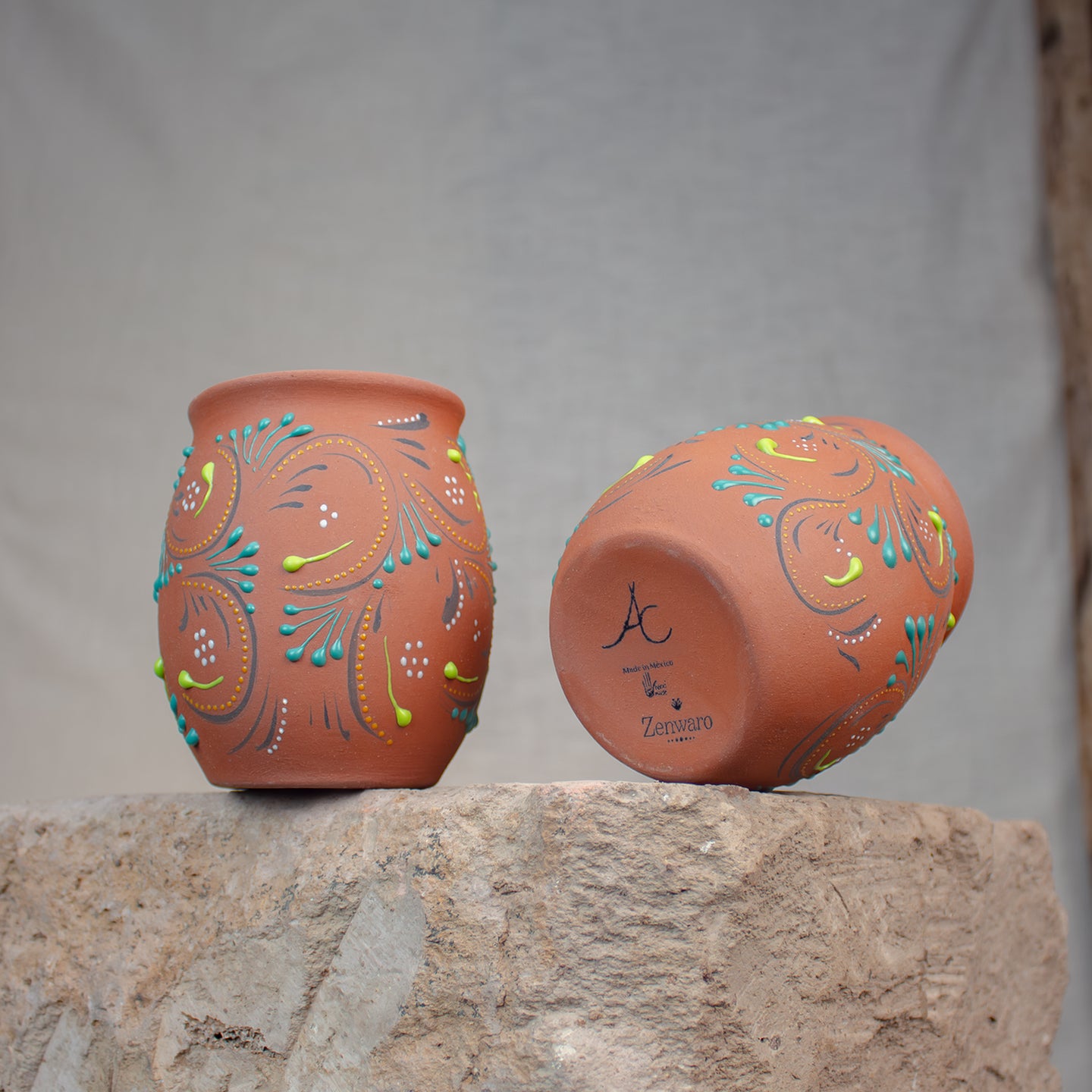 terracotta cups with Talavera patterns, on a stone table.