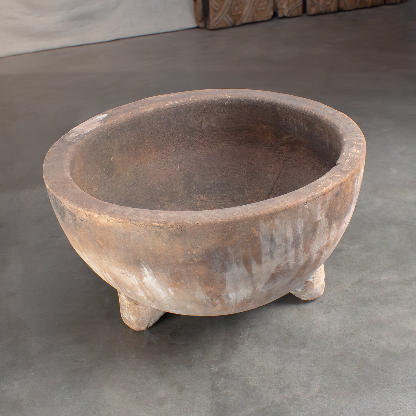 Vintage terracotta planter with feet on a gray concrete floor