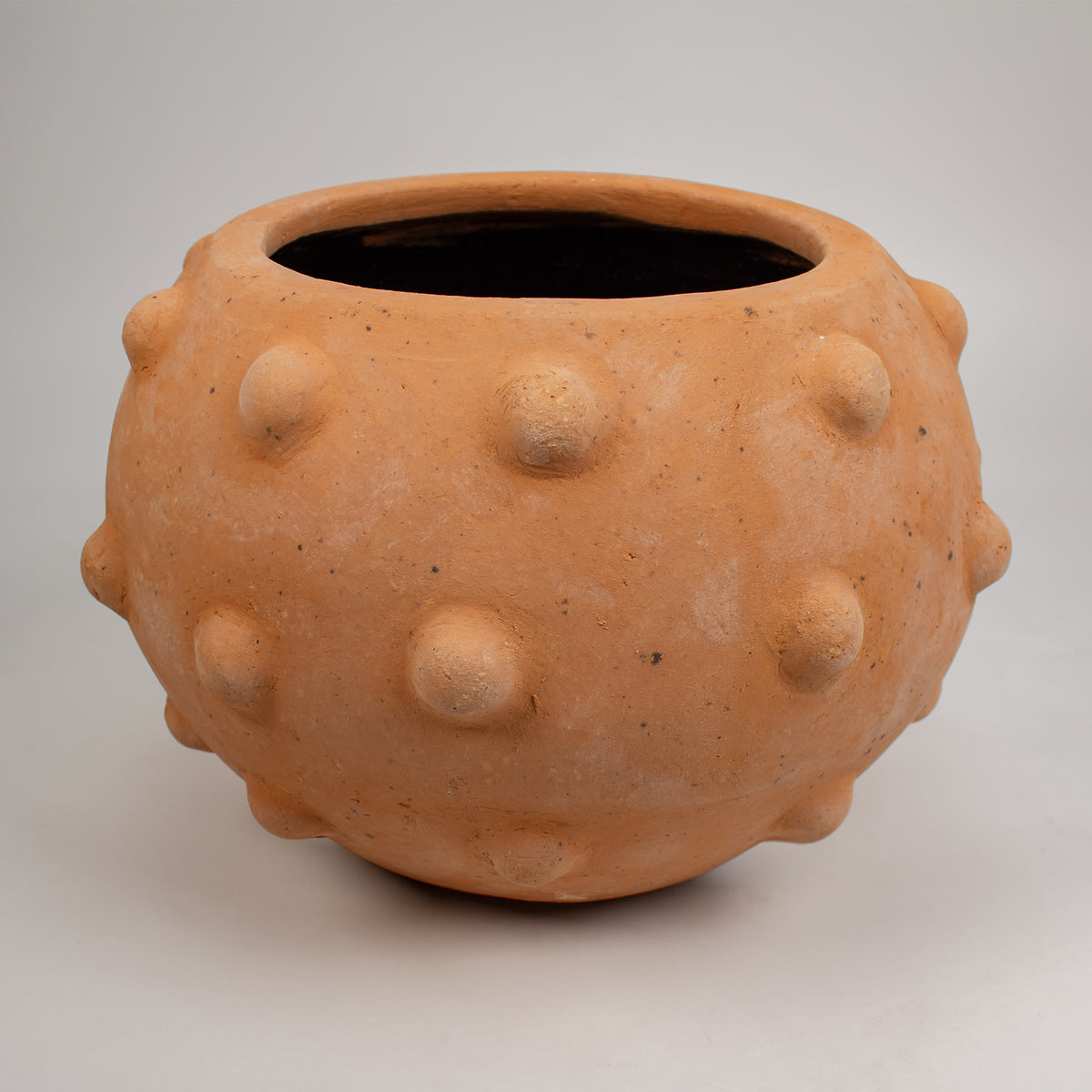 A terracotta with a textured, bumpy surface. Displayed on neutral light gray background.