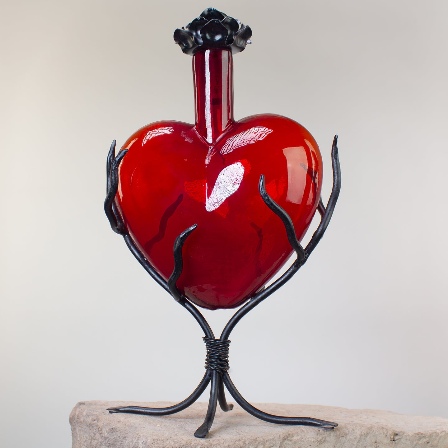 Red heart-shaped decanter on a black metal stand 