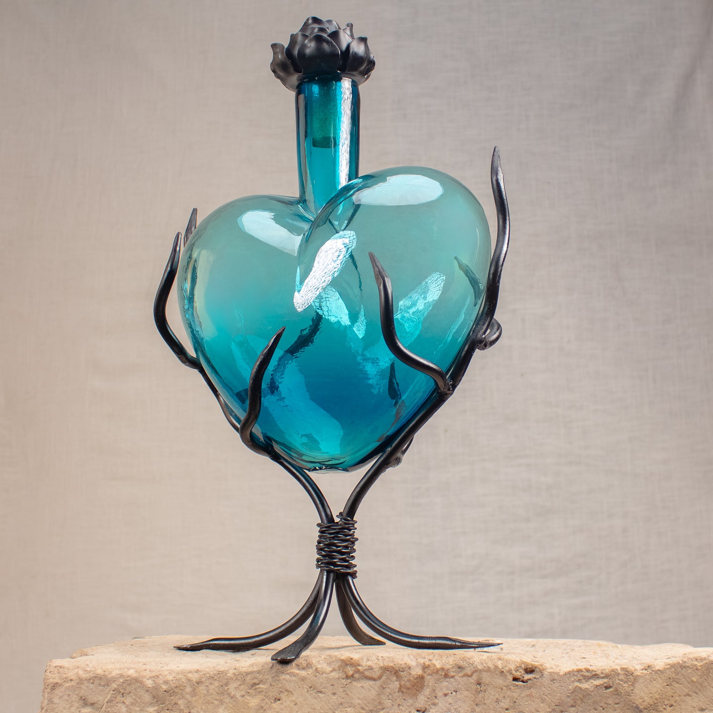 Heart shaped, blue glass decanter with  flower iron cap and vine stand.