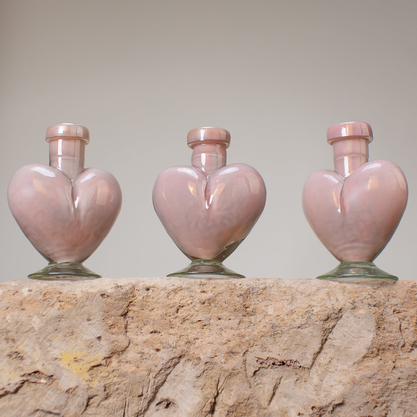Three pink heart-shaped small bottles. Hand blown from recycled glass.