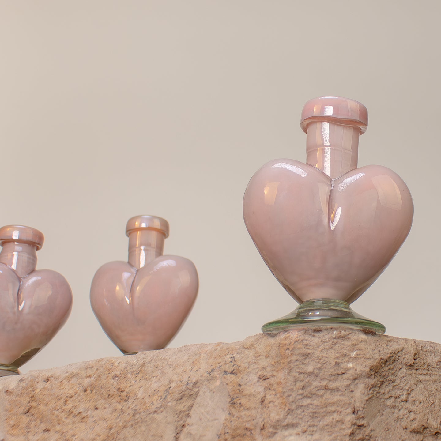 Heart-shaped blown glass vases. Small pink glass bottles.
